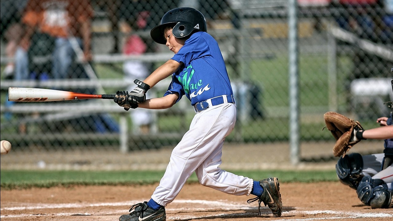 Young hitter in a blue jersey mid-swing during a game